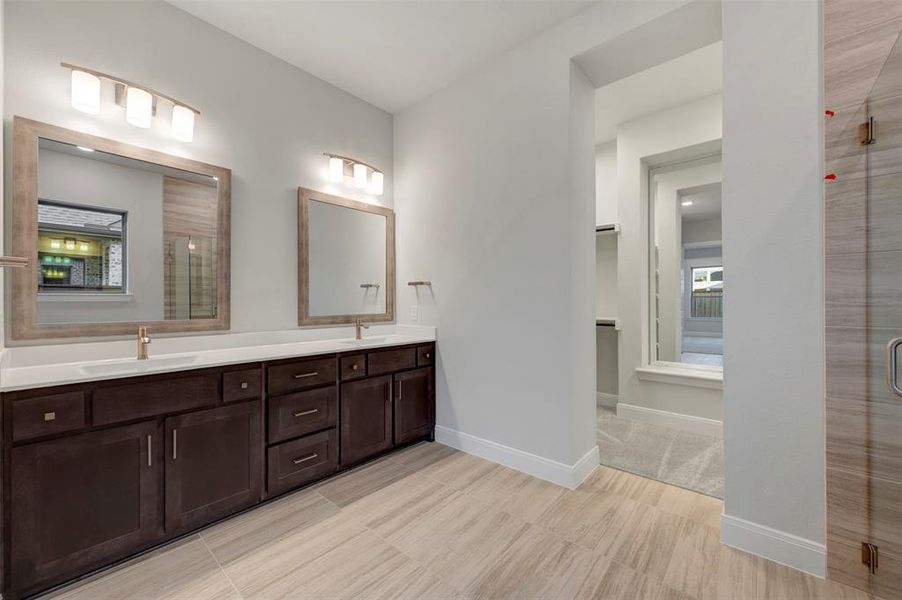 Full bathroom with a shower stall, double vanity, and a walk in closet