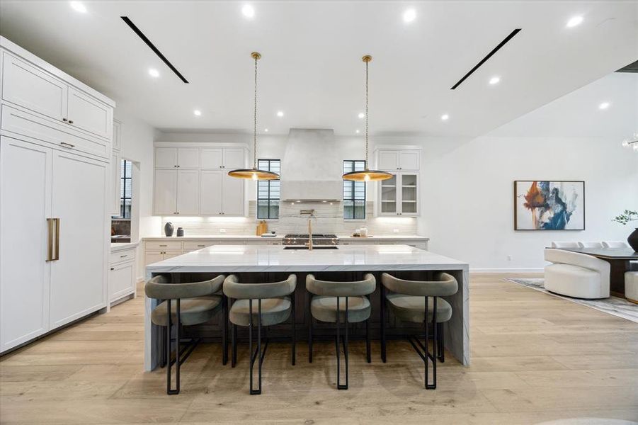 Gourmet kitchen equipped with high-end Thermador appliances, custom cabinetry, and a professional-grade stove. Elegant pendant lighting highlights the central island, ideal for meal preparation and entertaining.