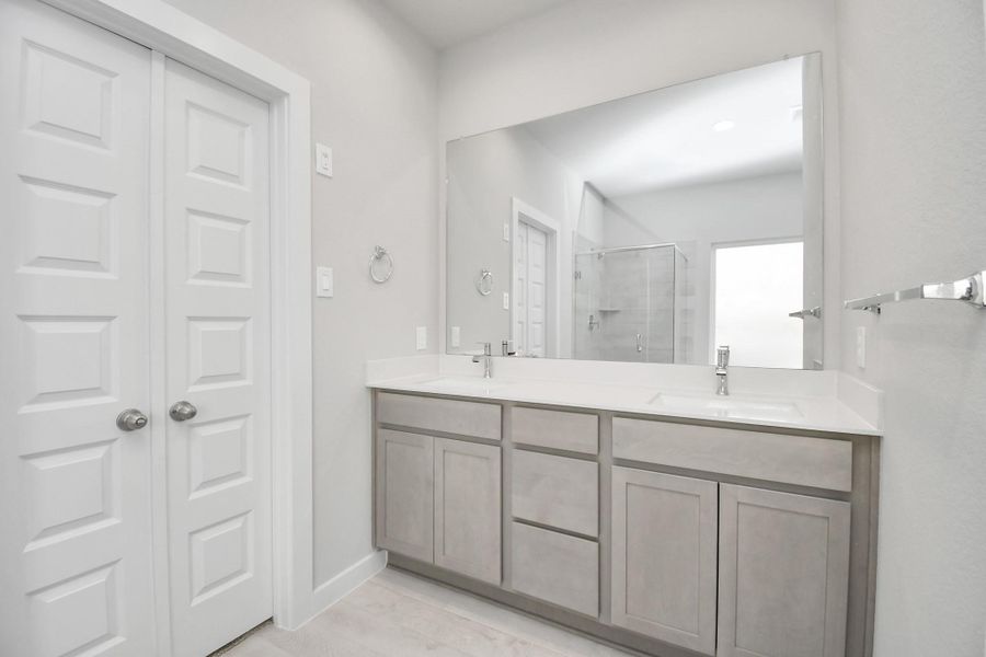 Elevate your daily routine at the elegant vanity, now equipped with double sinks, light countertops, modern hardware, and beautiful recessed lights. Sample photo of completed home with similar floor plan. Actual colors and selections may vary.
