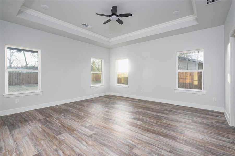 Unfurnished room with ornamental molding, wood finished floors, a tray ceiling, and ceiling fan