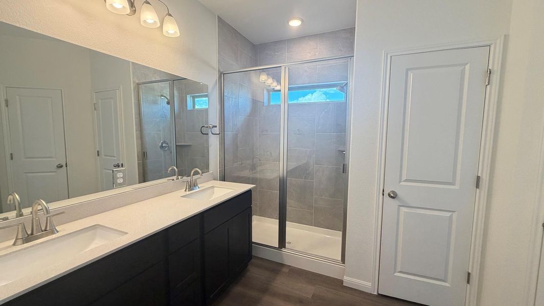 Dual vanity sinks complement a spacious walk-in shower with sleek tile and glass. Dual vanity sinks complement a spacious walk-in shower with sleek tile and glass.