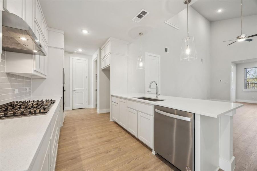 Kitchen with sink, light hardwood / wood-style flooring, appliances with stainless steel finishes, white cabinetry, and range hood