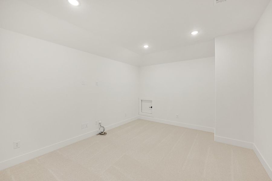 Empty room with white walls, beige carpet, recessed lighting, and a small wall access panel