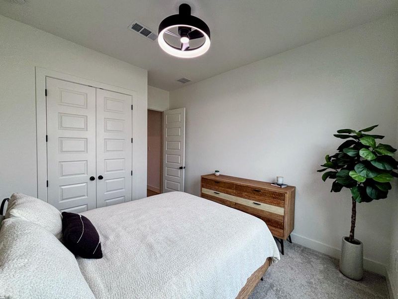 Cozy bedroom #2 with neutral walls and carpet, featuring a modern light fixture. Includes a double-door closet.