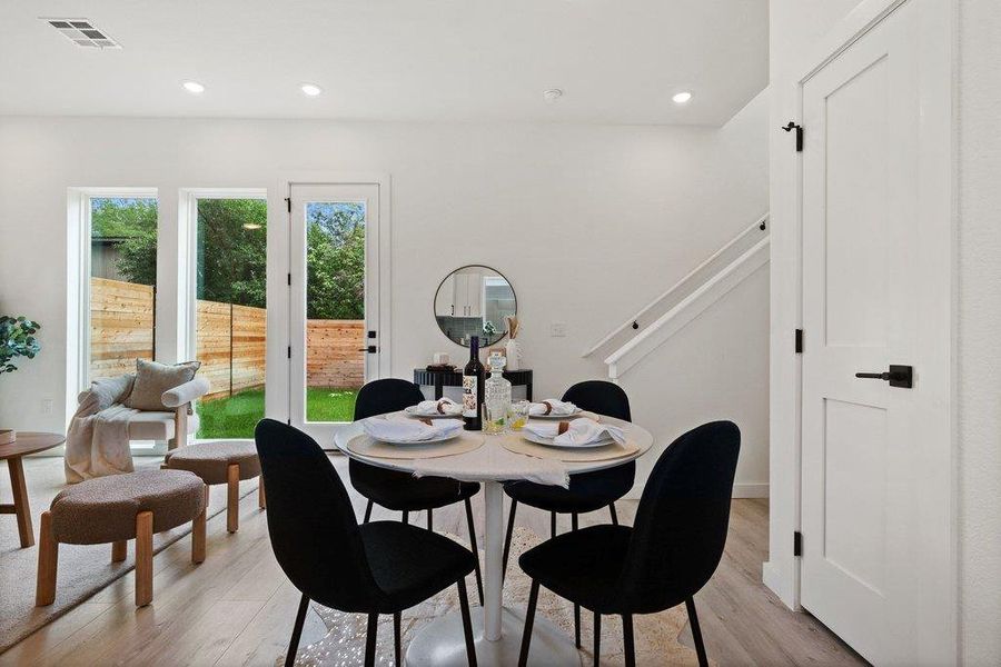 The interior features light-toned flooring, white walls, and a white staircase with a black handrail