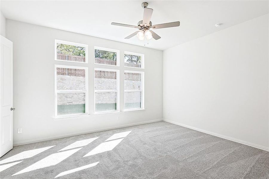 Carpeted spare room featuring ceiling fan