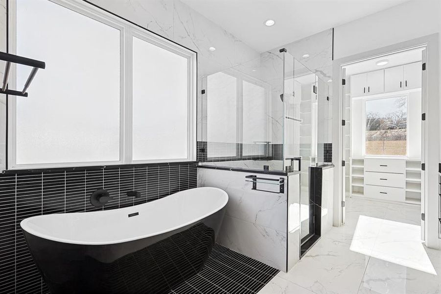 Bathroom featuring light marble finish floors, tile walls, a soaking tub, a marble finish shower, and a walk in closet Bathroom featuring light marble finish floors, tile walls, a soaking tub, a marble finish shower, and a walk in closet