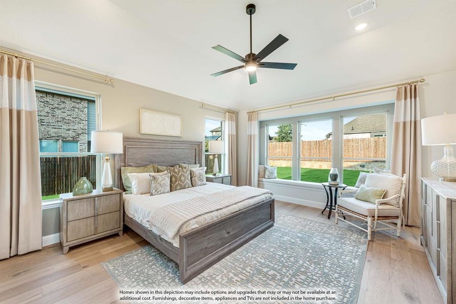 Spacious master bedroom with wood-frame bed, ceiling fan, hardwood floors, and large windows with backyard views