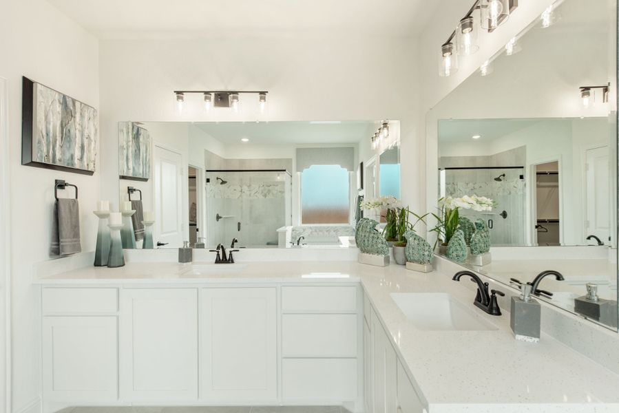 Master bathroom with dual vanities, white cabinets, quartz countertops, and glass shower in background Master bathroom with dual vanities, white cabinets, quartz countertops, and glass shower in background