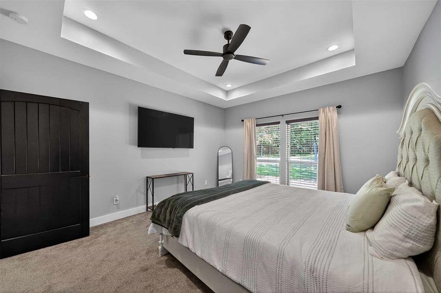 Bedroom with a tray ceiling, carpet, ceiling fan, and recessed lighting Bedroom with a tray ceiling, carpet, ceiling fan, and recessed lighting