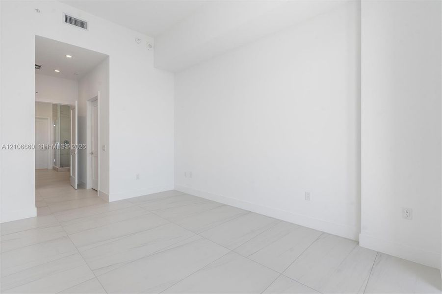 High-ceiling interior featuring smooth white walls, large-format tile flooring with marble-style veining, recessed lighting, and solid-core interior doors