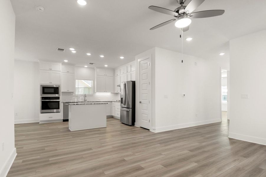Kitchen featuring open floor plan, a kitchen island, white cabinets, stainless steel appliances, and recessed lighting Kitchen featuring open floor plan, a kitchen island, white cabinets, stainless steel appliances, and recessed lighting