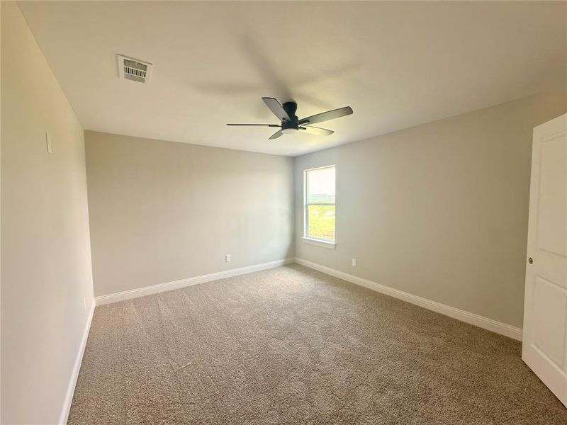 Carpeted room featuring a ceiling-mounted fan, a single window with white trim, and a white paneled door