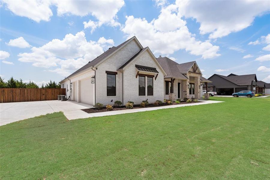 View of front of house with a garage, a front yard, and central AC unit