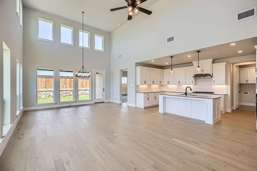 Kitchen with a high ceiling, open floor plan, ceiling fan, backsplash, and baseboards Kitchen with a high ceiling, open floor plan, ceiling fan, backsplash, and baseboards