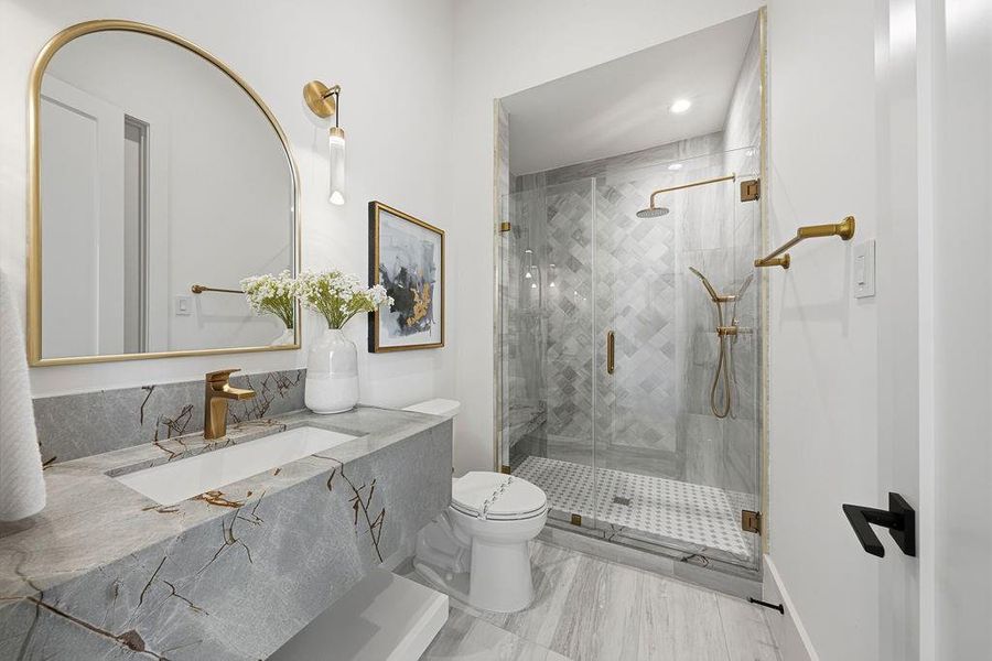 This is a compact yet luxurious full-bath (powder room) designed with modern finishes, gold accents, and a statement stone vanity, creating an elegant and sophisticated feel