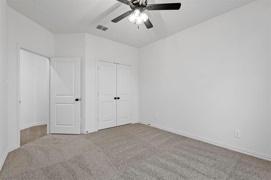 Unfurnished bedroom featuring carpet flooring, ceiling fan, and a closet