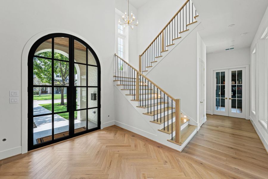 Another view highlighting the architectural details of the entry, including a wide staircase w/ wood handrail & iron balusters. A wall of Sierra Pacific windows brings in abundant natural light. A A Visual Comfort chandelier adds a refined finishing touch, completing this elegant introduction to the home. Clean lines & elevated finishes carry throughout. French doors to the right lead to the study and door to right leads to formal powder room and a spacious under-stair walk-in closet. Another view highlighting the architectural details of the entry, including a wide staircase w/ wood handrail & iron balusters. A wall of Sierra Pacific windows brings in abundant natural light. A A Visual Comfort chandelier adds a refined finishing touch, completing this elegant introduction to the home. Clean lines & elevated finishes carry throughout. French doors to the right lead to the study and door to right leads to formal powder room and a spacious under-stair walk-in closet.