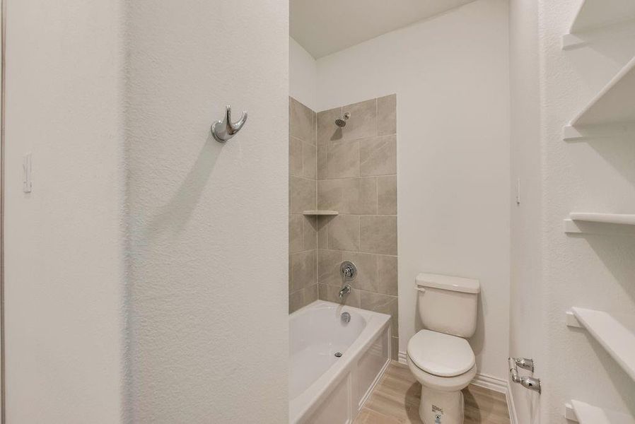 Bathroom with hardwood / wood-style floors, toilet, and tiled shower / bath