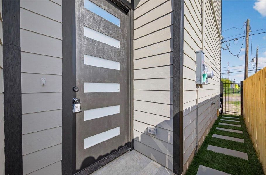 Modern entry experience with a statement 8' front door featuring frosted glass inlays, contemporary hardware, and clean-lined siding, offering privacy while allowing natural light to filter inside.