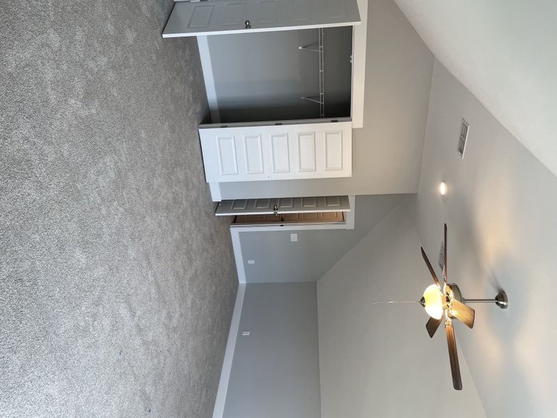 Upstairs spacious bonus room with vaulted ceilings, a ceiling fan, and a closet with double doors.