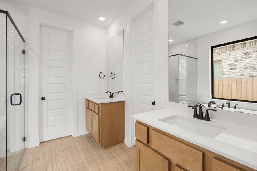 The primary bathroom has two separate sink areas. You also have the toilet closed off with a linen closet as well.