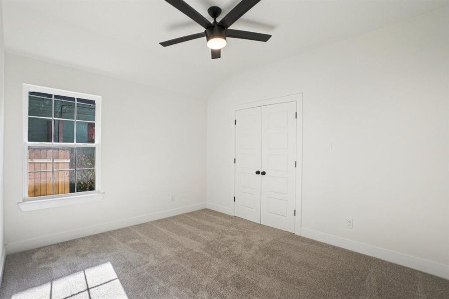 Spare room featuring carpet flooring, vaulted ceiling, and a ceiling fan Spare room featuring carpet flooring, vaulted ceiling, and a ceiling fan