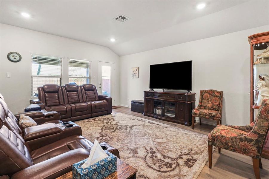 Living room with light wood finished floors, vaulted ceiling, and recessed lighting