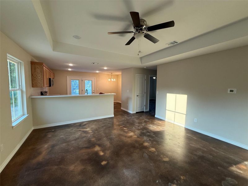 Unfurnished living room with plenty of natural light, a tray ceiling, and finished concrete floors Unfurnished living room with plenty of natural light, a tray ceiling, and finished concrete floors