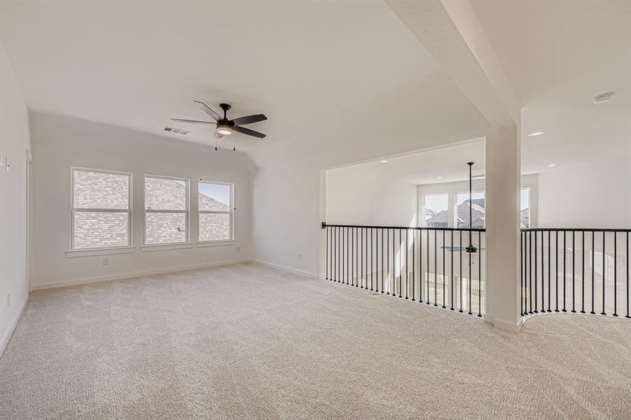 Empty room with a ceiling fan and light colored carpet
