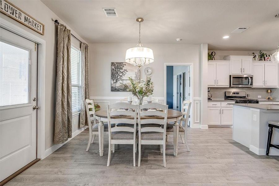 Dining room with light wood-style flooring, visible vents, and an inviting chandelier