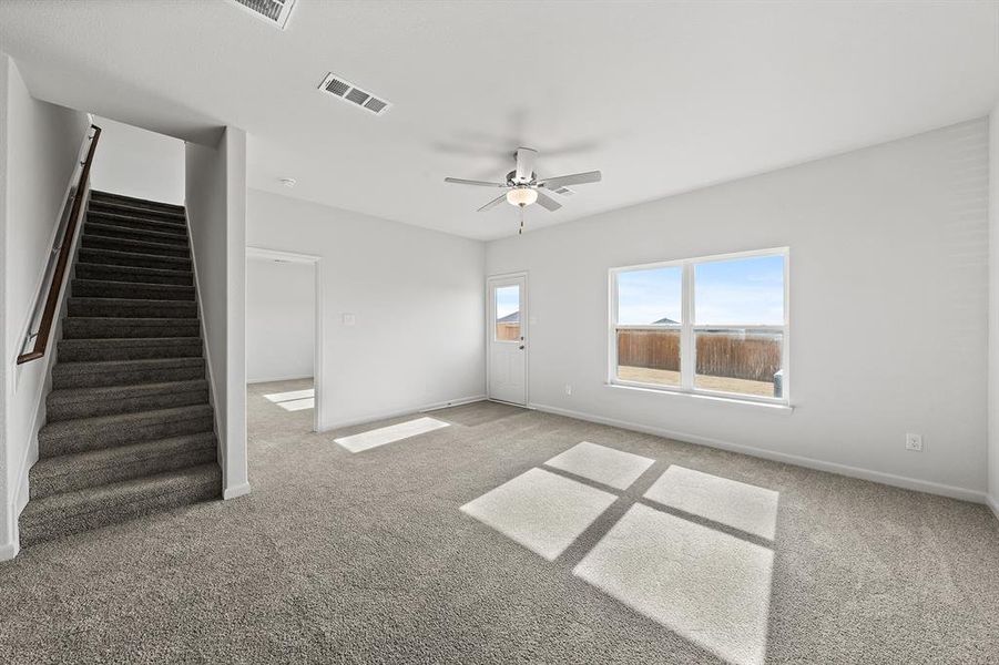 Unfurnished room with carpet, a ceiling fan, visible vents, baseboards, and stairs