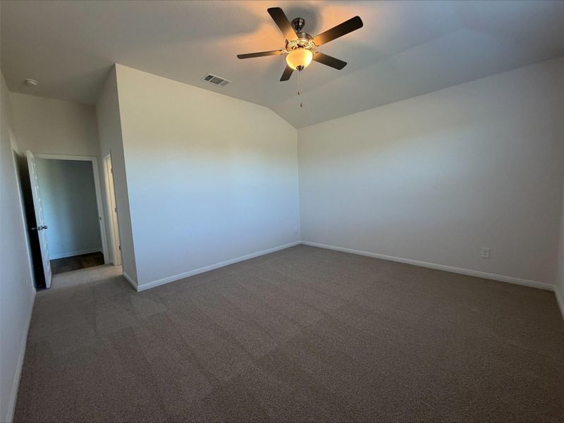 Unfurnished room featuring carpet flooring, lofted ceiling, and a ceiling fan