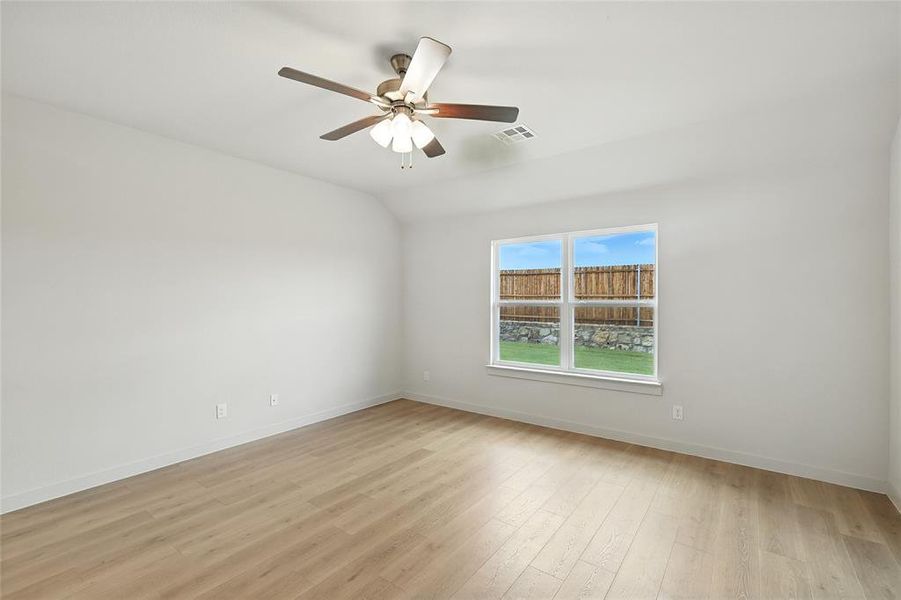 Unfurnished room with light wood-style flooring, lofted ceiling, and a ceiling fan Unfurnished room with light wood-style flooring, lofted ceiling, and a ceiling fan