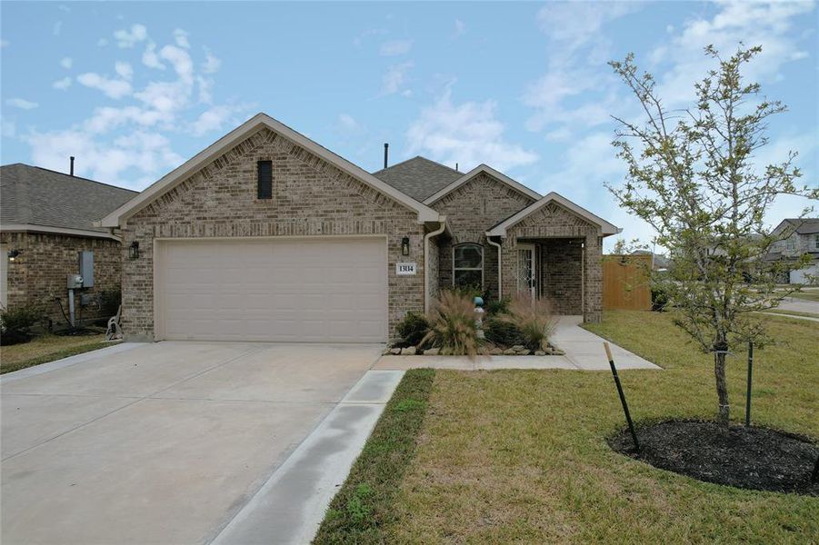 This photo features a charming brick home with a welcoming front entrance. It has a covered porch, decorative glass door, and well-maintained landscaping. The pathway leading to the front door enhances the inviting feel of the property.