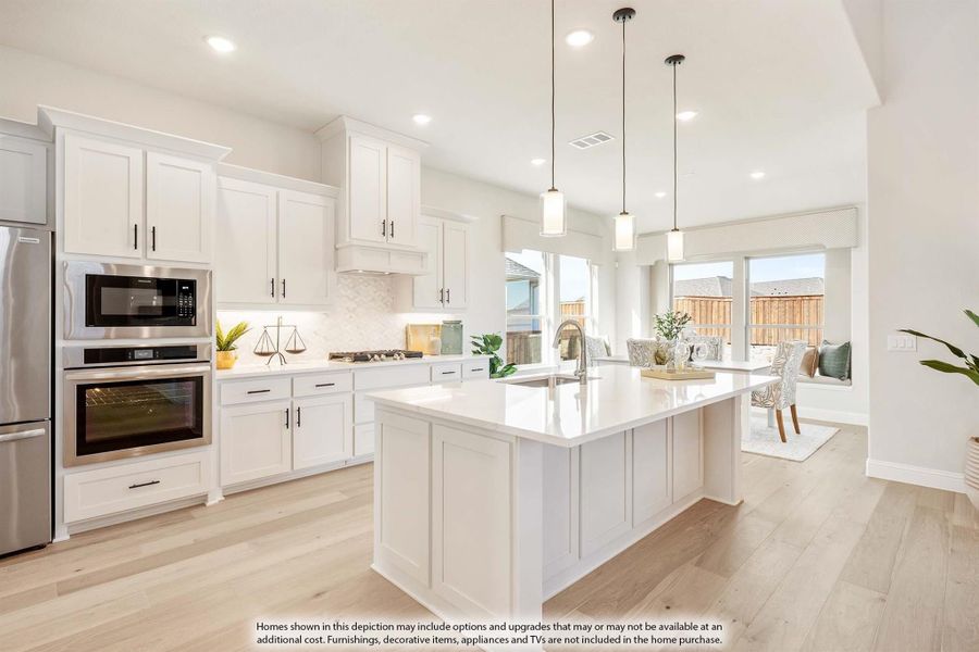 Kitchen with white cabinets, large island, stainless steel appliances, and light hardwood floors open to dining area
