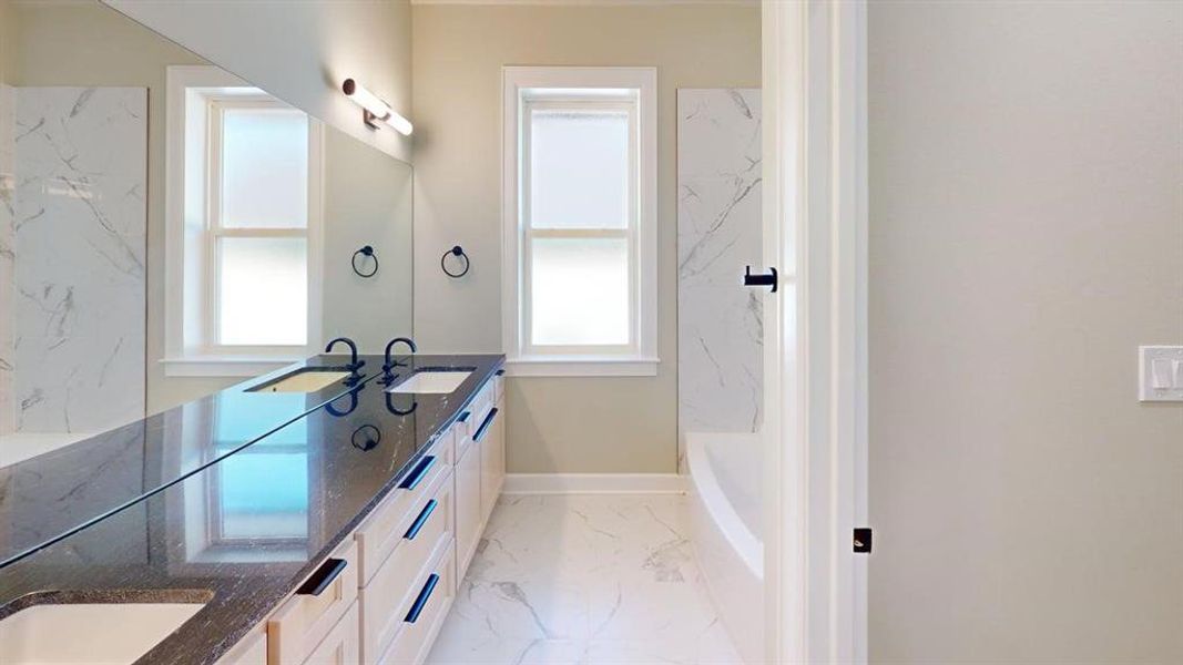 Bathroom featuring marble finish floors, double vanity, plenty of natural light, and baseboards