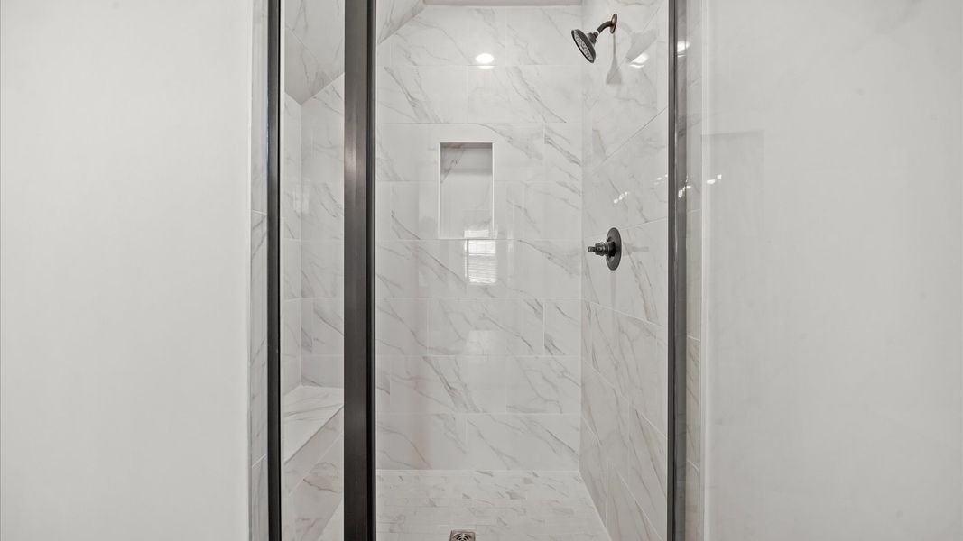 Notable primary suite with dual vanities and tiled walk-in shower in this prime DRB Homes townhome