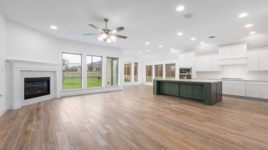 Kitchen with a fireplace, white cabinetry, light hardwood / wood-style flooring, and an island with sink