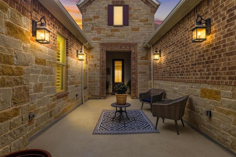 Enter through an Elegant Wrought Iron Gate into a Private Courtyard featuring Four Carriage Lights, Warm Ambiance, and a Welcoming Sitting Area.