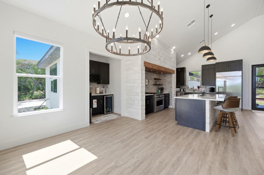 Vaulted ceilings and wood-plank flooring frame this open-concept kitchen under a striking iron chandelier.