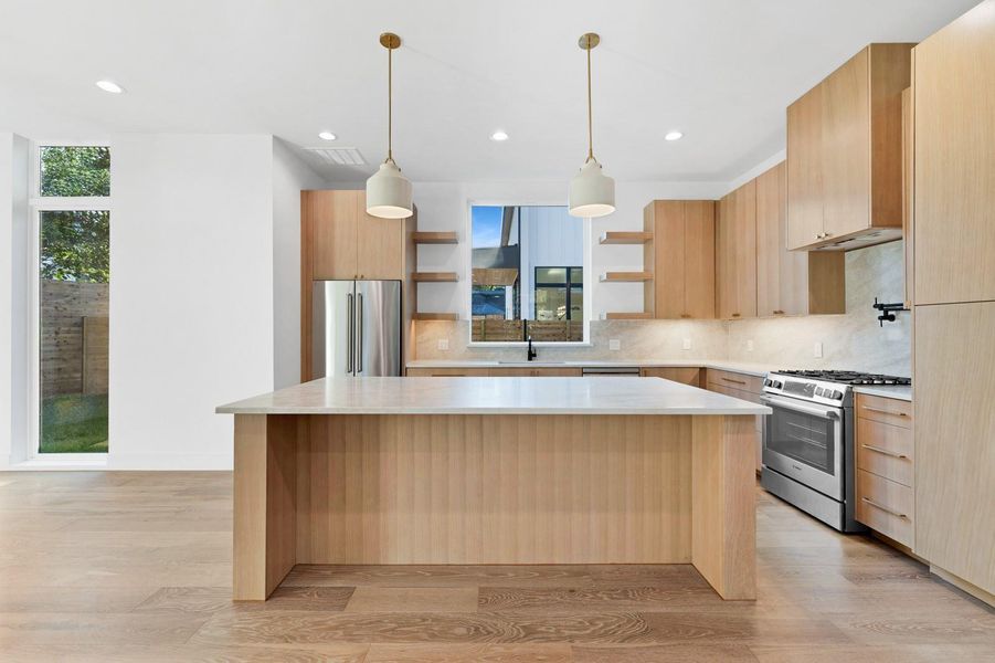 Kitchen with light brown cabinetry, stainless steel appliances, light wood-style floors, backsplash, and open shelves