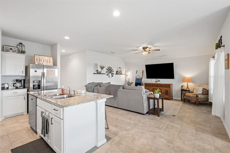 Kitchen featuring open floor plan, white cabinets, stainless steel appliances, a kitchen island with sink, and recessed lighting