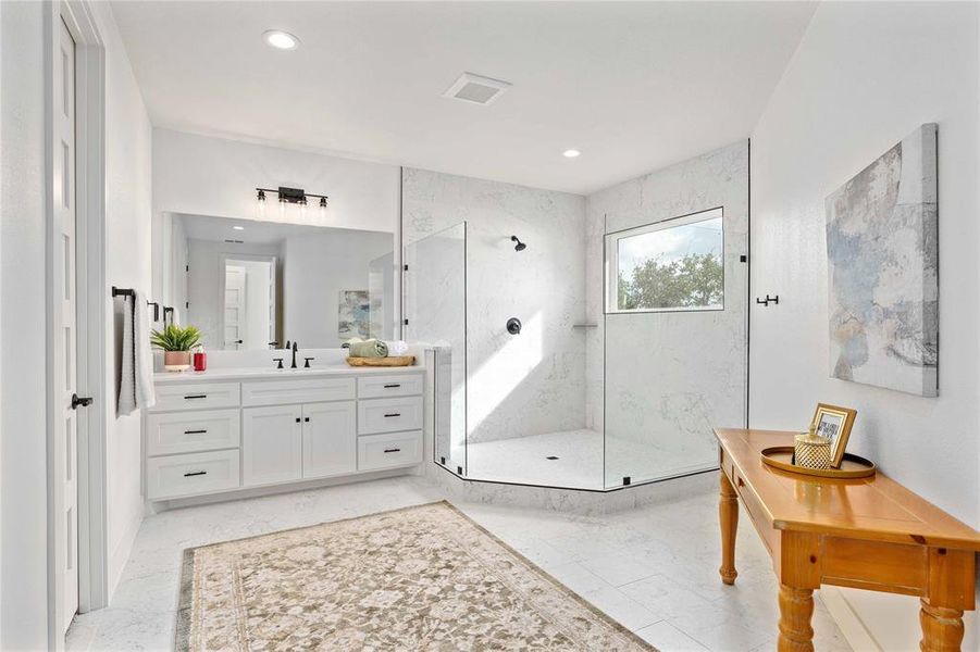 Bathroom featuring vanity, a marble finish shower, light marble finish flooring, and recessed lighting