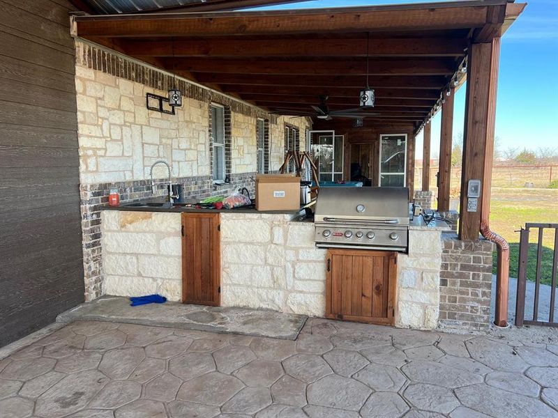 View of patio with an outdoor kitchen, a grill, sink, and ceiling fan