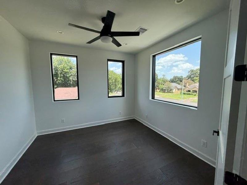 Bright and inviting upstairs bedroom with large windows offering scenic views and abundant natural light.