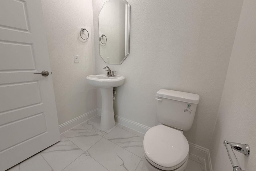 Half bath featuring baseboards and light marble finish flooring