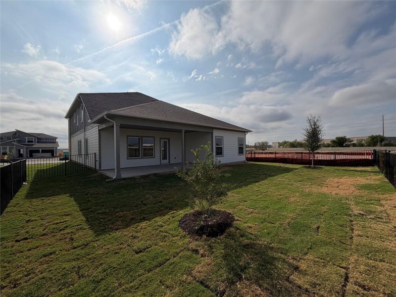 Back of property with a fenced backyard, a patio, and a shingled roof
