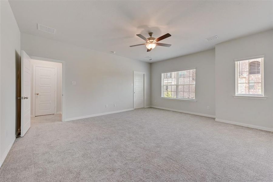 Spare room featuring light carpet, a wealth of natural light, and ceiling fan