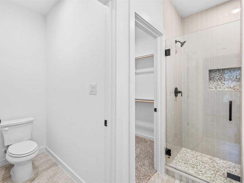 Full bath with a spacious closet and a stall shower